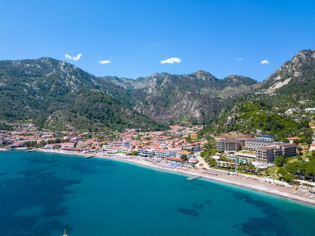 Turunç'ta Ev Almak ve Yaşamak: Gayrimenkul Rehberi
Turunç'ta ev almak, Marmaris'te denize yakın, doğayla iç içe ve merkezden daha sakin bir yaşam arayanların değerlendirebileceği seçeneklerden biridir. Turunç; sahili, çevresindeki dağlık yapı ve daha düşük yoğunluklu yerleşimiyle Marmaris'in farklı karaktere sahip bölgelerinden biri olarak öne çıkar.
Bölgede ev ararken yalnızca manzara veya sahile yakınlık üzerinden karar vermek yeterli değildir. Konutun bulunduğu yükseklik, araç ulaşımı, otopark imkanı, güneş alma durumu ve dört mevsim kullanım koşulları birlikte değerlendirilmelidir.
Marmaris genelindeki güncel konut seçeneklerini Marmaris satılık daire ve ev ilanları sayfasından inceleyebilirsiniz.
Turunç'ta Ev Almak Nasıl Bir Yaşam Sunar?
Turunç'ta ev almak, Marmaris merkezin yoğunluğundan uzaklaşmak ancak deniz ve doğayla bağlantısını korumak isteyenler için farklı bir yaşam seçeneği sunabilir.
Turunç'ta yaşam yaz aylarında daha hareketli hale gelir. Sahil, restoranlar, konaklama tesisleri ve turizm hareketliliği özellikle sezon döneminde bölgenin karakterini belirler. Kış döneminde ise daha sakin bir yaşam düzeni oluşabilir.
Bu nedenle yıl boyunca Turunç'ta yaşamayı planlayanların yalnızca yaz aylarındaki koşulları değil, kış dönemindeki günlük ihtiyaçlarını da düşünmesi gerekir.
Marketlere, sağlık hizmetlerine, ana ulaşım yollarına ve Marmaris merkeze erişim ev seçiminde dikkate alınması gereken unsurlar arasındadır.
Turunç'ta Hangi Konut Tipleri Bulunur?
Turunç'ta portföy durumuna göre farklı gayrimenkul tipleriyle karşılaşmak mümkündür.
Bölgede dönemsel olarak:
Apartman daireleri
Bahçe katı konutlar
Dubleksler
Müstakil evler
Villalar
Site içerisindeki konutlar
Deniz manzaralı evler
Teraslı ve bahçeli konutlar
satışa çıkabilir.
Özellikle eğimli bölgelerde bulunan konutlar daha geniş deniz ve doğa manzarası sunabilir. Ancak yüksek konum, günlük araç kullanımı ve yokuşlu ulaşım gibi farklı koşulları da beraberinde getirebilir.
Villa veya müstakil ev arıyorsanız Marmaris satılık villa ve müstakil evler sayfasındaki güncel seçenekleri inceleyebilirsiniz.
Turunç'ta Ev Almak İçin Nelere Dikkat Edilmeli?
Turunç'ta ev almak isteyenlerin konutu yalnızca ilan fotoğrafları üzerinden değerlendirmemesi önemlidir.
Turunç'un arazi yapısı nedeniyle aynı mahallede birkaç sokaklık mesafe bile konutun manzarasını, yol eğimini, araç ulaşımını ve sahile erişimini önemli ölçüde değiştirebilir.
Satın alma öncesinde özellikle sahile gerçek mesafe, yolun eğimi, otopark imkanı, bina yaşı, evin cephesi, güneş alma durumu, balkon veya teras kullanımı, tapu niteliği ve iskan durumu kontrol edilmelidir.
Yıl boyunca kullanılacak bir konut söz konusuysa nem, yalıtım ve ısıtma sistemi de göz ardı edilmemelidir.
Deniz Manzaralı Evlerde Nelere Bakılmalı?
Turunç'ta ev arayanların önemli bir kısmı deniz manzarasını öncelikli kriter olarak değerlendirebilir.
Ancak manzaralı bir ev satın alırken yalnızca manzaranın ne kadar geniş olduğuna bakmak yeterli değildir.
Manzaranın evin hangi odalarından görüldüğü, balkon veya terasın kullanım alanı, yakın çevredeki yapılaşma ve eve ulaşım koşulları birlikte değerlendirilmelidir.
Yüksek noktadaki bir konut daha geniş bir manzaraya sahip olabilir ancak araçsız günlük yaşamı zorlaştırabilir.
Marmaris bölgesindeki benzer seçenekler için Marmaris deniz manzaralı satılık ev ve villa ilanları sayfasını inceleyebilirsiniz.
Yazlık İçin Turunç'ta Ev Almak
Turunç'ta ev almak, yazlık kullanım amacıyla Marmaris'te alternatif arayanlar açısından da değerlendirilebilir.
Yazlık bir evde sahile yakınlık, balkon, teras, bahçe veya havuz gibi özellikler daha fazla önem kazanabilir.
Ancak konut yılın yalnızca belirli dönemlerinde kullanılacaksa evin boş kaldığı zamanlarda bakımının nasıl yapılacağı da düşünülmelidir.
Site içerisindeki konutlarda ortak alan, havuz ve peyzaj bakımı daha düzenli olabilir. Bunun karşılığında aidat ve ortak giderler bulunabilir.
Marmaris'teki diğer yazlık seçenekleri Marmaris satılık yazlık evler sayfasından karşılaştırabilirsiniz.
Turunç Sürekli Yaşam İçin Uygun mu?
Turunç yalnızca yazlık kullanım amacıyla değerlendirilen bir yerleşim değildir. Doğru konut seçildiğinde sürekli yaşam için de düşünülebilir.
Ancak sürekli yaşam planlayanların günlük alışveriş, ulaşım, sağlık hizmetleri ve Marmaris merkeze gitme ihtiyacını önceden değerlendirmesi gerekir.
Özellikle sık sık Marmaris merkeze gidilecekse evin ana yola ulaşımı ve araç kullanım kolaylığı önemli hale gelir.
Kış döneminde güneş alma süresi ve konutun yalıtımı da yaşam konforunu etkileyebilir.
Turunç'ta Konut Fiyatlarını Neler Etkiler?
Turunç'taki satılık konutların fiyatlarını tek başına metrekare üzerinden karşılaştırmak doğru olmayabilir.
Denize mesafe, manzara, bina yaşı, tadilat durumu, evin bulunduğu kat, bahçe veya teras kullanımı ve otopark imkanları fiyat üzerinde etkili olabilir.
Özellikle deniz manzaralı ve yüksek konumlu evlerde manzara önemli bir değer unsuru haline gelirken sahile yürüme mesafesinde bulunan konutlarda konum farklı bir avantaj sağlayabilir.
Bu nedenle Turunç'ta ev almak için araştırma yapılırken mümkün olduğunca benzer özelliklerdeki taşınmazların karşılaştırılması gerekir.
Tapu ve Parsel Bilgilerini Kontrol Edin
Gayrimenkul satın alma sürecinde taşınmazın fiziksel özellikleri kadar resmi kayıtları da önemlidir.
Tapu niteliği, bağımsız bölüm bilgileri, arsa payı ve parsel bilgileri satın alma öncesinde kontrol edilmelidir.
Ada ve parsel bilgilerinin ilk incelemesi için Tapu ve Kadastro Genel Müdürlüğünün resmi TKGM Parsel Sorgu hizmetini kullanabilirsiniz.
Bölgedeki belediye hizmetleri ve güncel yerel bilgilere ulaşmak için Marmaris Belediyesi resmi internet sitesinden yararlanabilirsiniz.
Evi Yerinde Görmek Neden Önemli?
Turunç'ta ev almak isteyenler için taşınmazı yerinde görmek özellikle önemlidir.
Fotoğraflarda kısa görünen bir sahil mesafesi, bölgenin eğimli yapısı nedeniyle günlük kullanımda farklı hissedilebilir. Aynı şekilde çok güzel manzaraya sahip bir konutun araç ulaşımı veya otoparkı beklentiyi karşılamayabilir.
Yerinde inceleme sırasında evin yanı sıra sokağı, yakın çevresi, yol eğimi, otopark durumu ve sahile ulaşımı da kontrol edilmelidir.
Turunç'ta Ev Almak Hakkında Sonuç
Turunç'ta ev almak, Marmaris'te deniz ve doğayla iç içe daha sakin bir yaşam arayanlar için değerlendirilebilecek seçeneklerden biridir.
Ancak doğru konut seçiminde manzara kadar günlük yaşam koşulları, ulaşım, otopark, yapı durumu ve tapu bilgileri de önemlidir.
Yazlık kullanım için alınacak bir ev ile sürekli yaşam amacıyla tercih edilecek konutun özellikleri farklı olabileceğinden, satın alma öncesinde kullanım amacını belirlemek gerekir.
Turunç ve Marmaris genelindeki güncel portföyleri karşılaştırmak veya yerinde gösterim hakkında bilgi almak için Türker Günak Premium Emlak Ofisi – Marmaris Gayrimenkul Danışmanlığı sayfasını ziyaret edebilirsiniz.